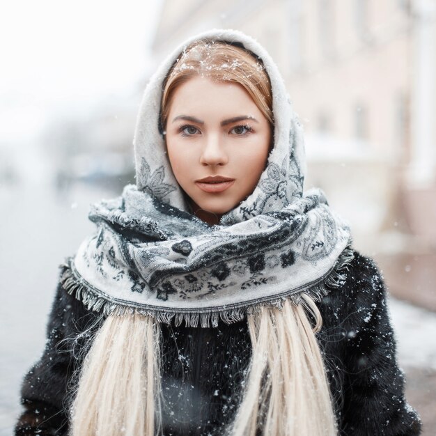 Mooie jonge vrouw in een modieuze sjaal op een winterse dag