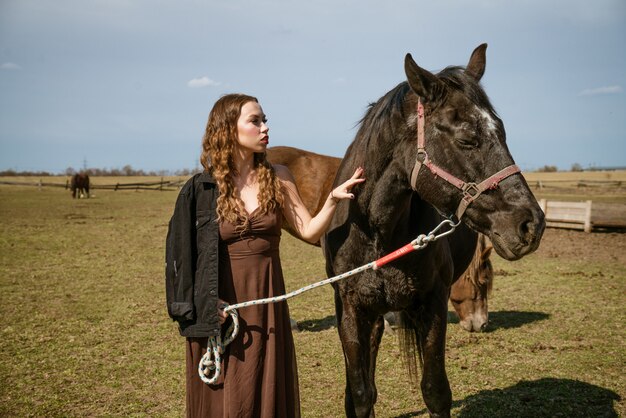 Mooie jonge vrouw in een veld met paarden. Aantrekkelijk fotomodel.