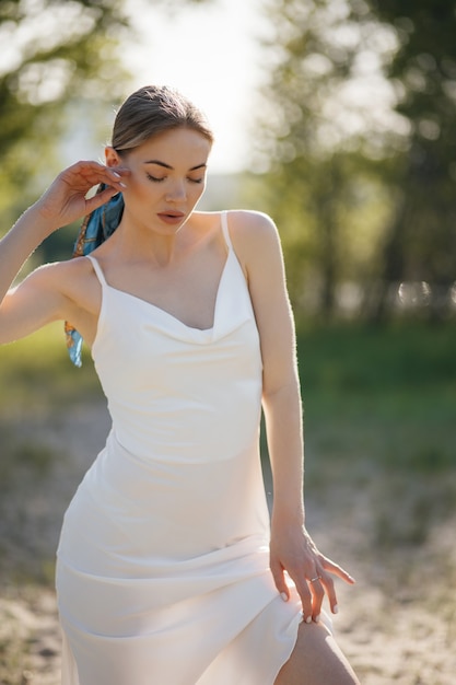 Mooie jonge vrouw in een witte jurk loopt in het park.