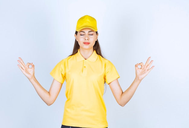 Mooie jonge vrouw in geel t-shirt en pet op zoek poseren op witte achtergrond.