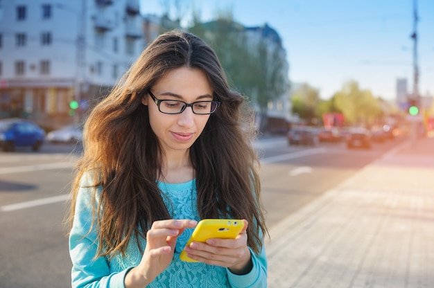 Mooie jonge vrouw in glazen met smartphone het schrijven