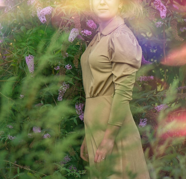 Foto mooie jonge vrouw in gouden jurk op buddleia veld van tarwe portret van inschrijving vrouw op een veld