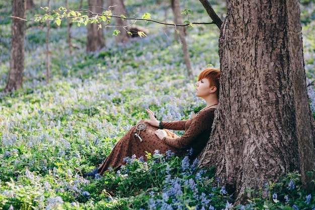 Mooie jonge vrouw in het bos met lentebloemen