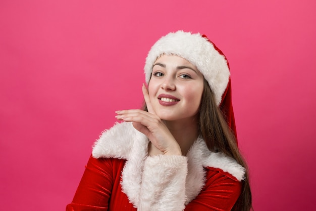 Mooie jonge vrouw in het kostuum van de Kerstman tegen de rode achtergrond.