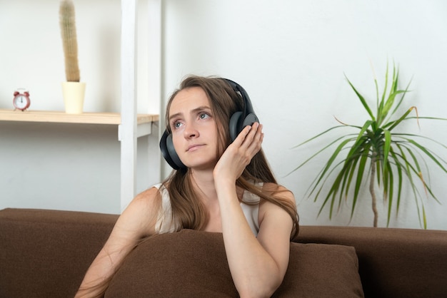 Mooie jonge vrouw in koptelefoon luistert zorgvuldig naar muziek.