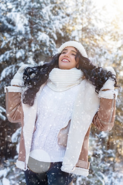 Mooie jonge vrouw in sneeuwval op de achtergrond van de winterbos Kerstmis of Nieuwjaarsvakantie