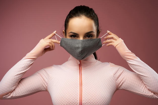 Mooie jonge vrouw in sportkleding die gezichtsmasker opdoet