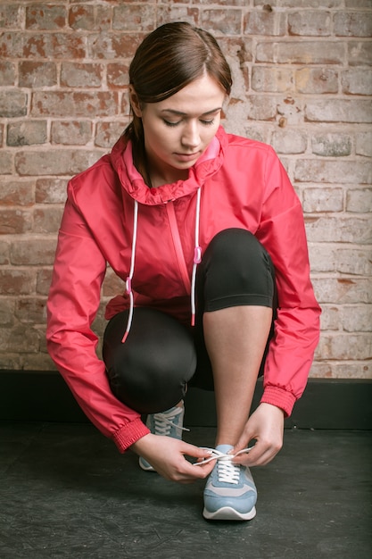 Foto mooie jonge vrouw in sportkleding stropdas schoenveters