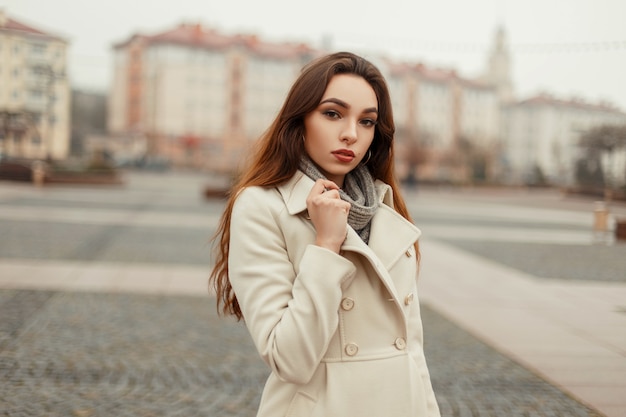 Mooie jonge vrouw in stijlvolle elegante herfstkleren poseren in de stad