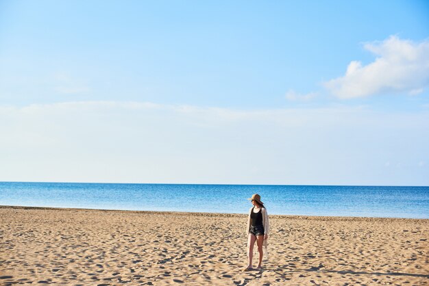 Mooie jonge vrouw in strohoed op het strand