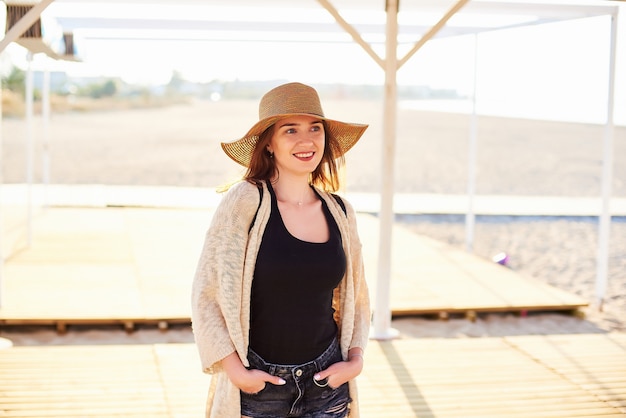 Mooie jonge vrouw in strohoed op het strand