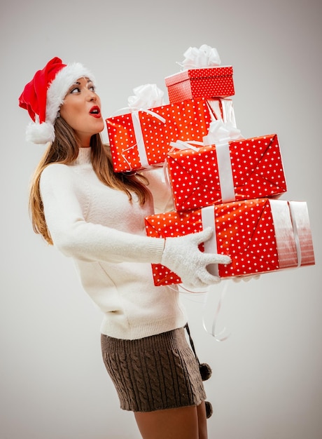 Mooie jonge vrouw in warme kleding met veel kerstcadeaus.