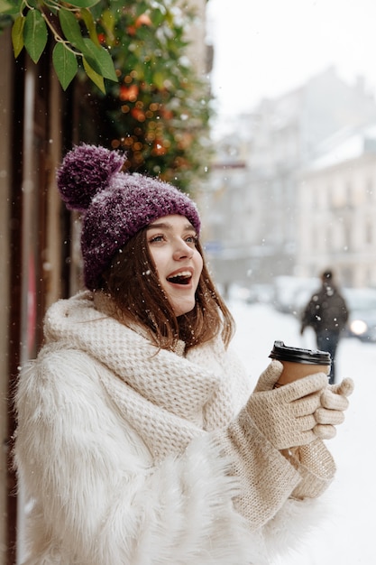 Mooie jonge vrouw in winter outfit wandelen tijdens sneeuwval