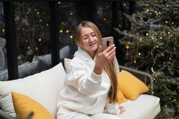 Foto mooie jonge vrouw in winterpak loopt tussen de dennenbomen en praat aan de telefoon