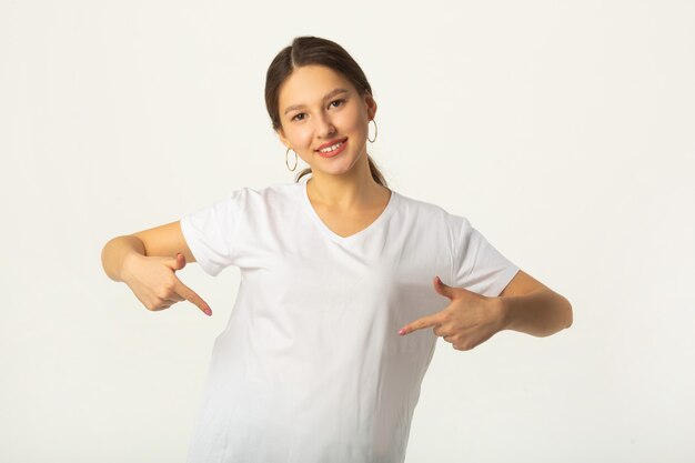 Mooie jonge vrouw in wit t-shirt op witte achtergrond met handgebaar