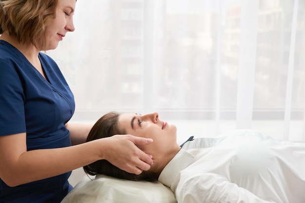 Mooie jonge vrouw krijgt een gezicht en een hoofdbehandeling bij schoonheidssalon