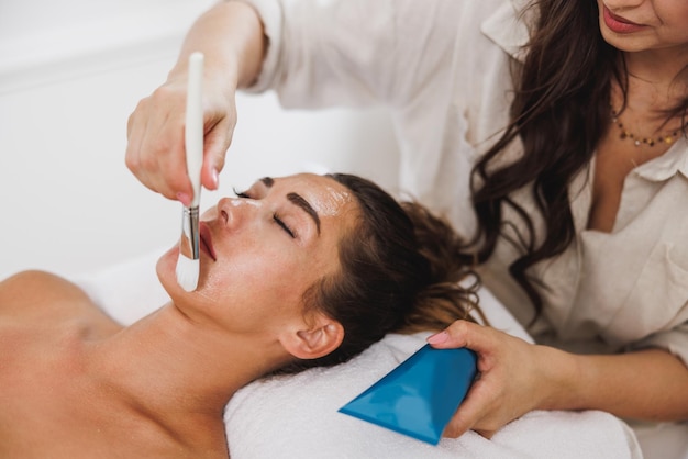 Mooie jonge vrouw krijgt een hydraterende maskerbehandeling in de schoonheidssalon.