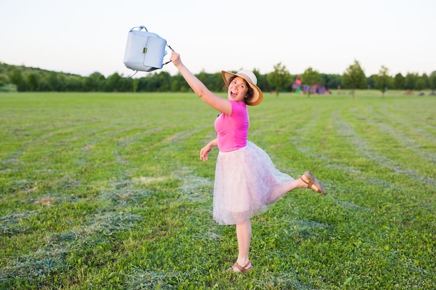 Mooie jonge vrouw lacht en danst buiten in een weiland tijdens zonsondergang