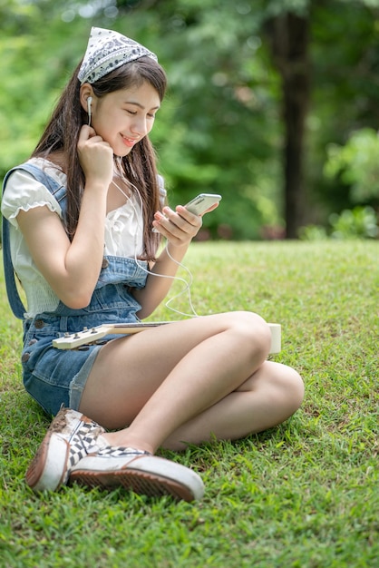 Mooie jonge vrouw meisje in beige shirt poseren in groene stad Park achtergrond Smile girl Listen