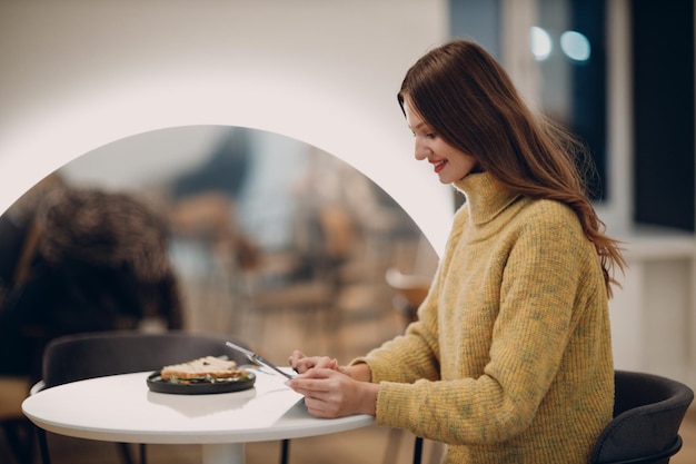 Mooie jonge vrouw met behulp van digitale tablet aan café tafel met kopje koffie