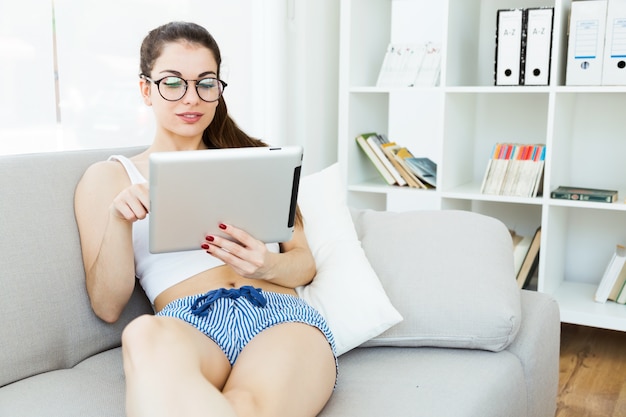 Mooie jonge vrouw met behulp van haar digitale tablet thuis.