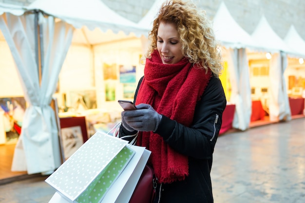 Mooie jonge vrouw met behulp van haar mobiele telefoon in de straat &#39;s nachts.