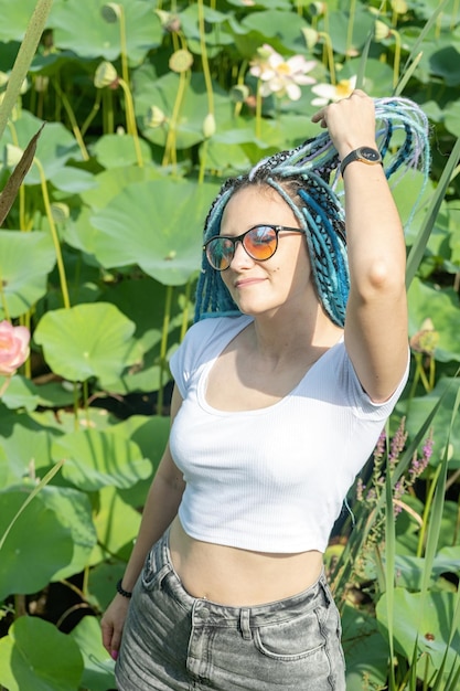 mooie jonge vrouw met blauwe afro lokken rusten op lotus meer genieten van de natuur