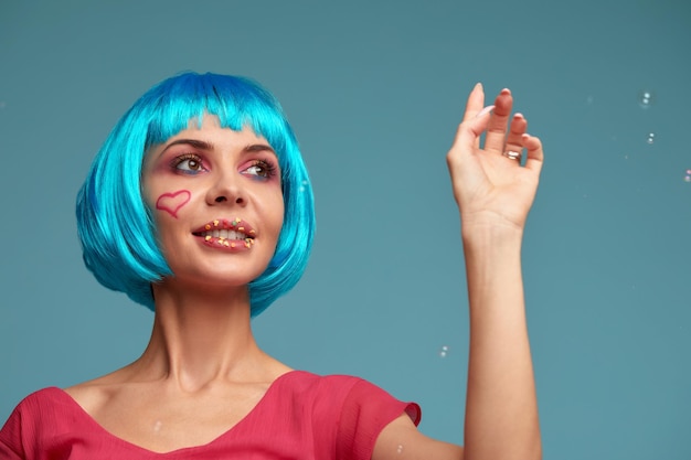 Mooie jonge vrouw met blauwe pruik en lichte make-up in zeepbellen Mannequin meisje met creatieve kleur make-up Vrouwen pop concept