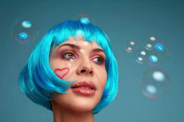 Mooie jonge vrouw met blauwe pruik en lichte make-up in zeepbellen Mannequin meisje met creatieve kleur make-up Vrouwen pop concept