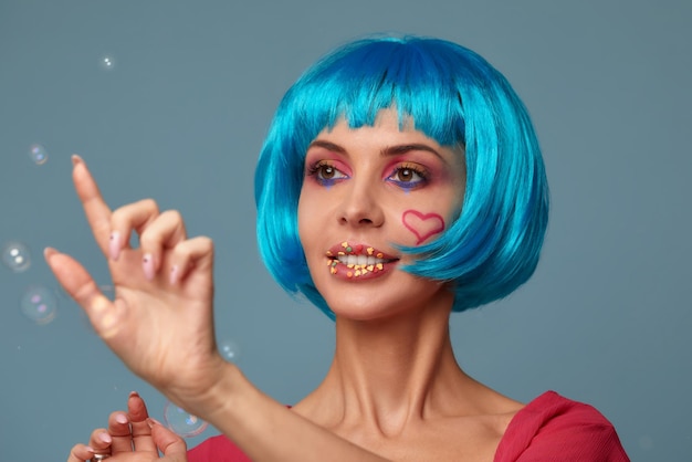 Mooie jonge vrouw met blauwe pruik en lichte make-up in zeepbellen Mannequin meisje met creatieve kleur make-up Vrouwen schoonheid make-up concept