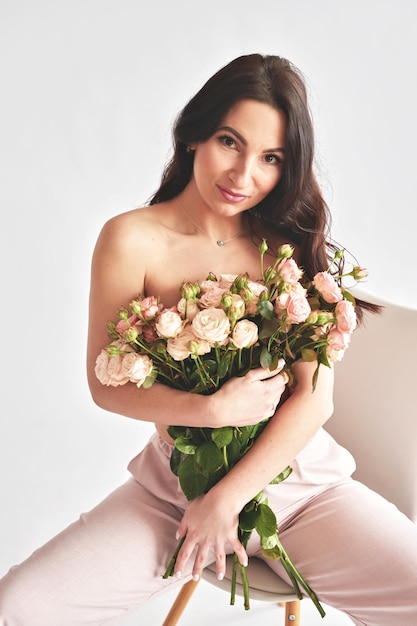 Mooie jonge vrouw met boeket bloemen van rozen Internationale Vrouwendag