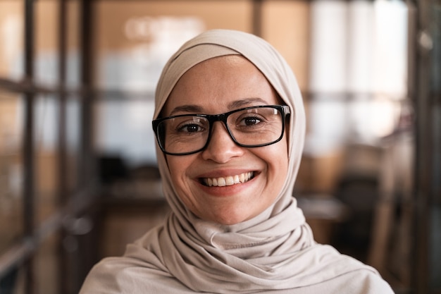 Mooie jonge vrouw met de hijab die op kantoor werkt