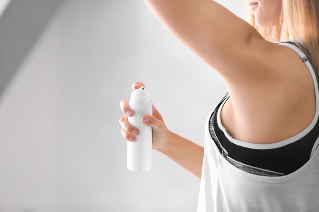 Foto mooie jonge vrouw met deodorant op lichte achtergrond