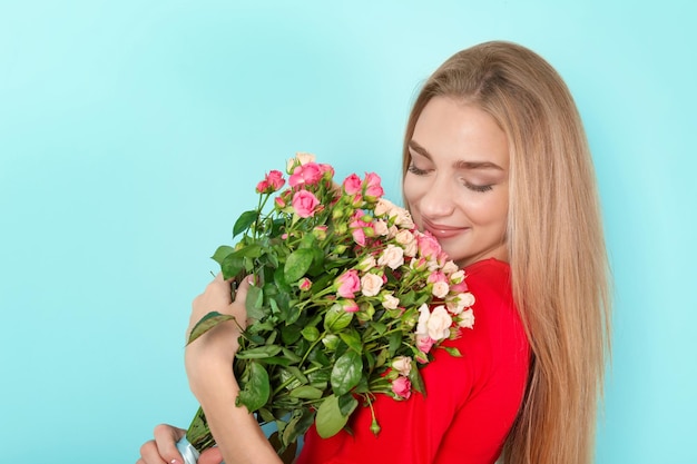 Mooie jonge vrouw met een boeket rozen op een achtergrond in kleur