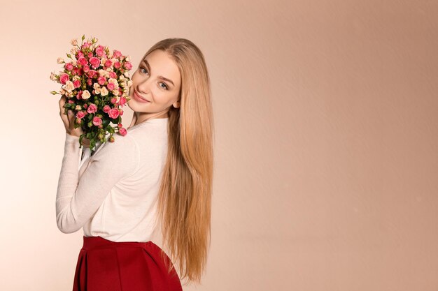 Mooie jonge vrouw met een boeket rozen op een achtergrond in kleur