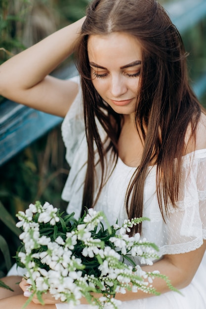 Mooie jonge vrouw met een boeket van wilde bloemen met make-up buitenshuis