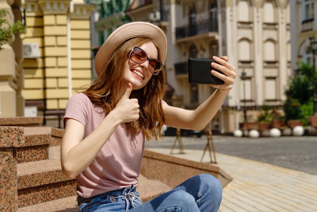 Mooie jonge vrouw met een hoed die een selfie neemt