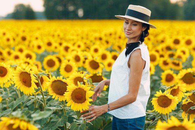 Mooie jonge vrouw met een hoed op een veld van zonnebloemen