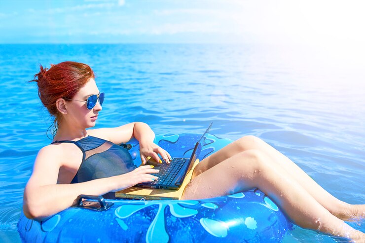 Mooie jonge vrouw met een opblaasbare ring en een laptop ontspannen in de zee. Workaholic-concept
