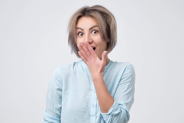 Mooie jonge vrouw met een verlegen gebaar die naar je kijkt