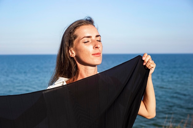 Mooie jonge vrouw met gesloten ogen op de achtergrond van de zee en de lucht