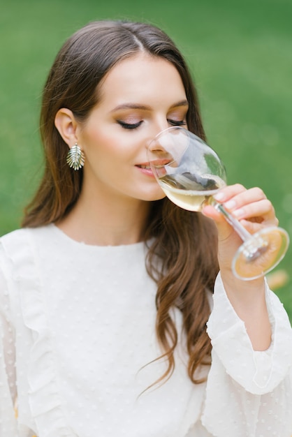 Mooie jonge vrouw met glas wijn op groene achtergrond