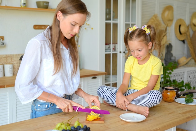 mooie jonge vrouw met haar dochter bereidt ontbijt in de keuken familie theekransje