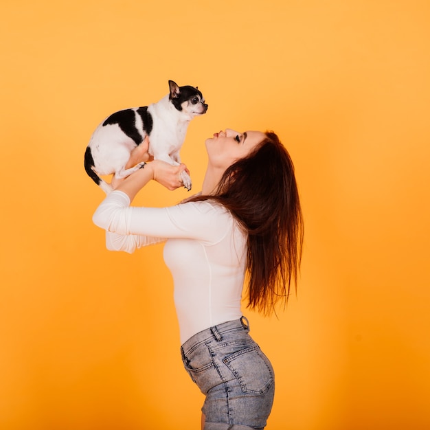 Mooie jonge vrouw met haar hond op een gele achtergrond.