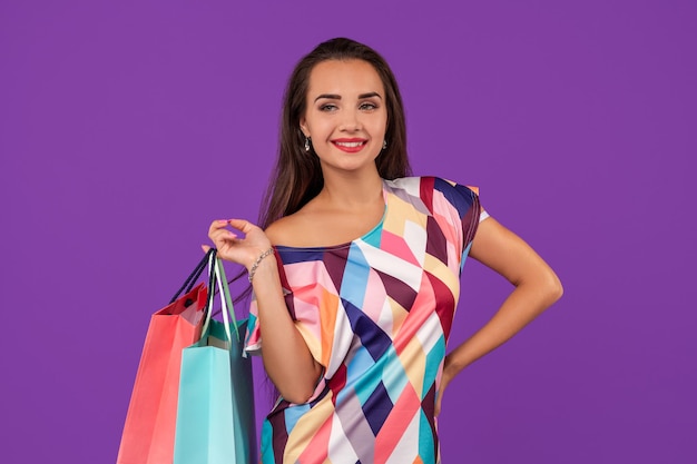 Mooie jonge vrouw met kleurrijke boodschappentassen op de prachtige paarse achtergrond