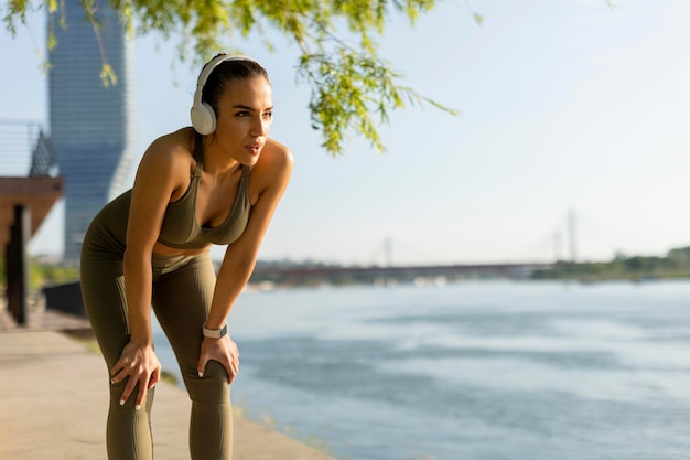 Mooie jonge vrouw met koptelefoon die een pauze neemt tijdens het sporten buiten