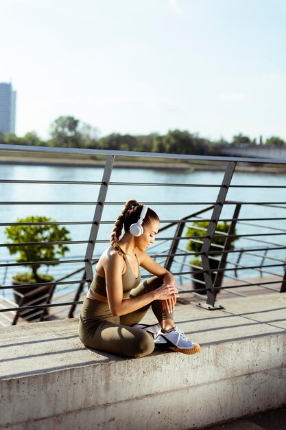 Mooie jonge vrouw met koptelefoon neemt een pauze na het hardlopen in stedelijk gebied