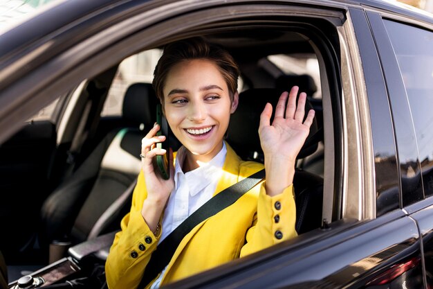 Mooie jonge vrouw met kort haar rijdt auto in de stad