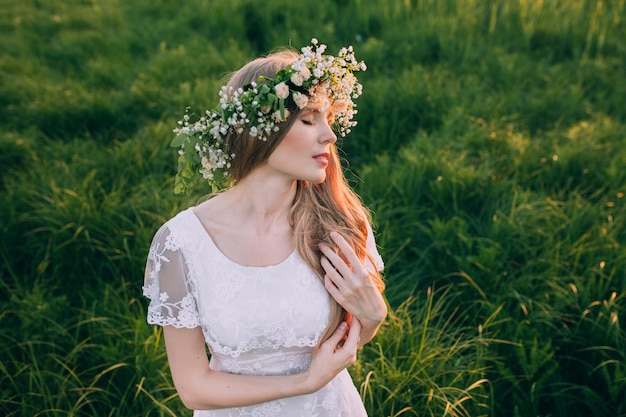 Mooie jonge vrouw met kroon van wildflowers in hun haar.