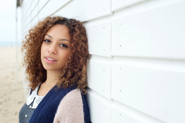 Mooie jonge vrouw met krullend haar die in openlucht stellen